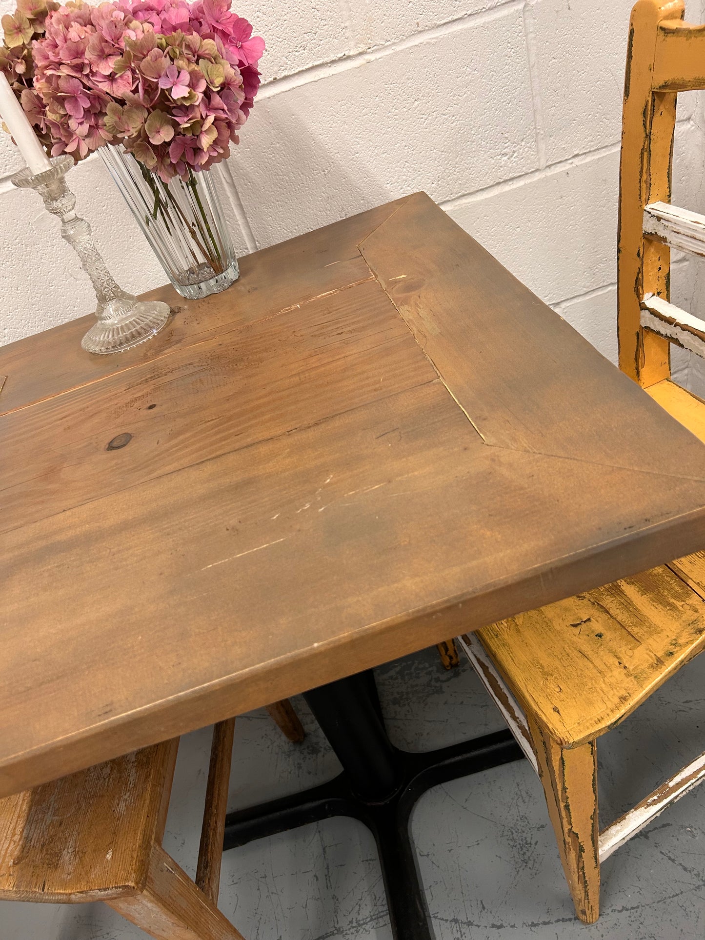 Rustic Preloved two seater table with thick wooden top and black metal base.