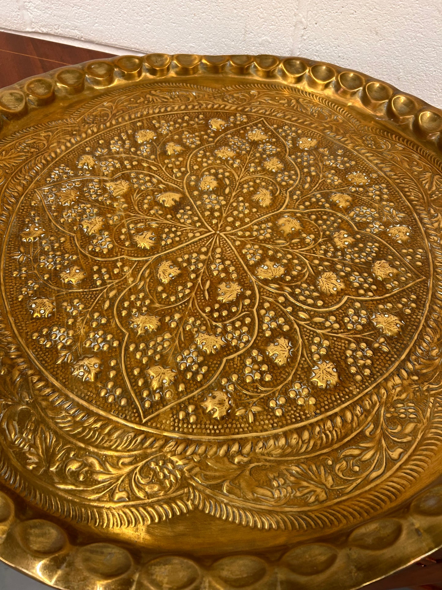A large brass eastern charger with embossed foliate design
