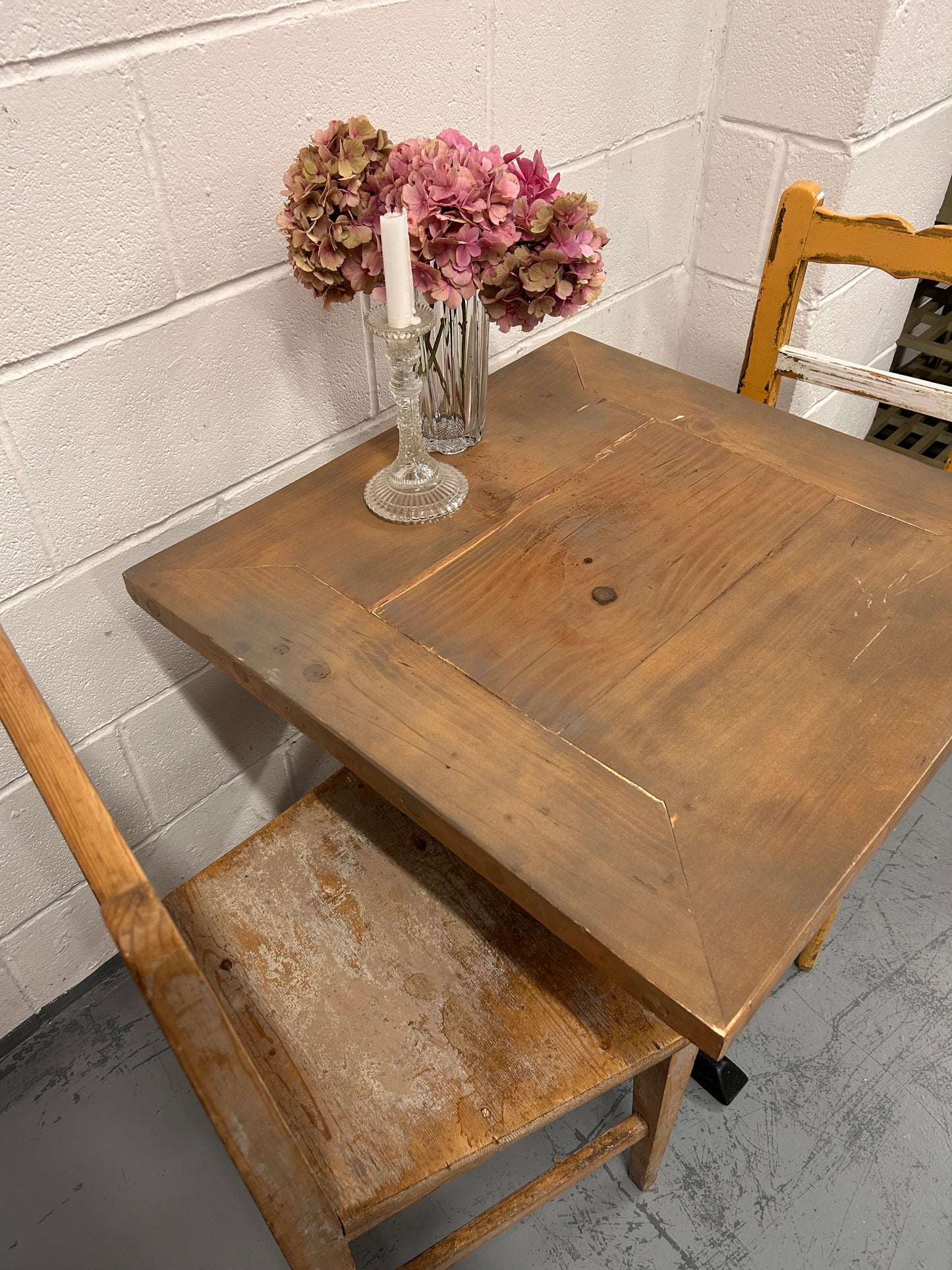 Rustic Preloved two seater table with thick wooden top and black metal base.