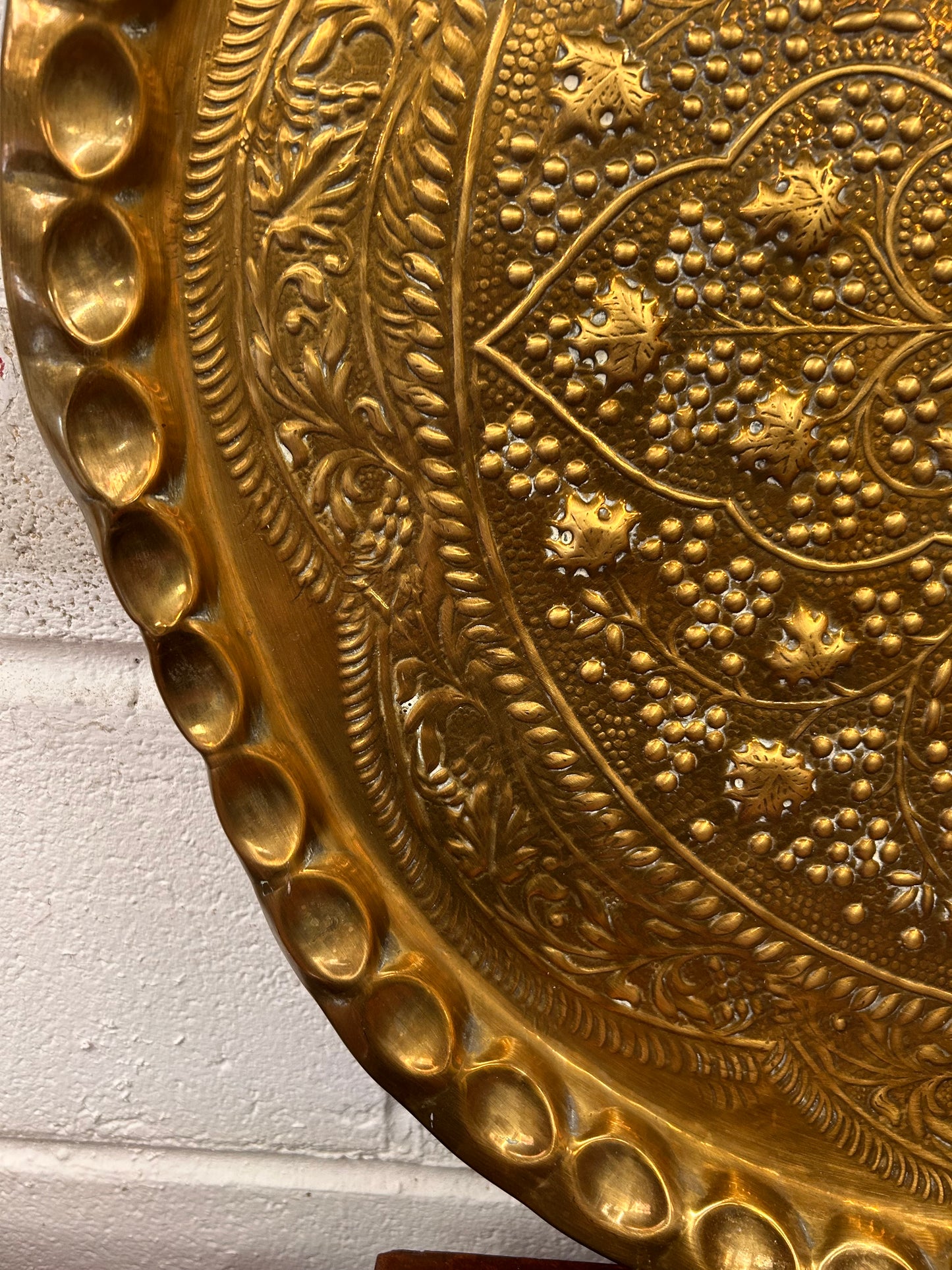 A large brass eastern charger with embossed foliate design