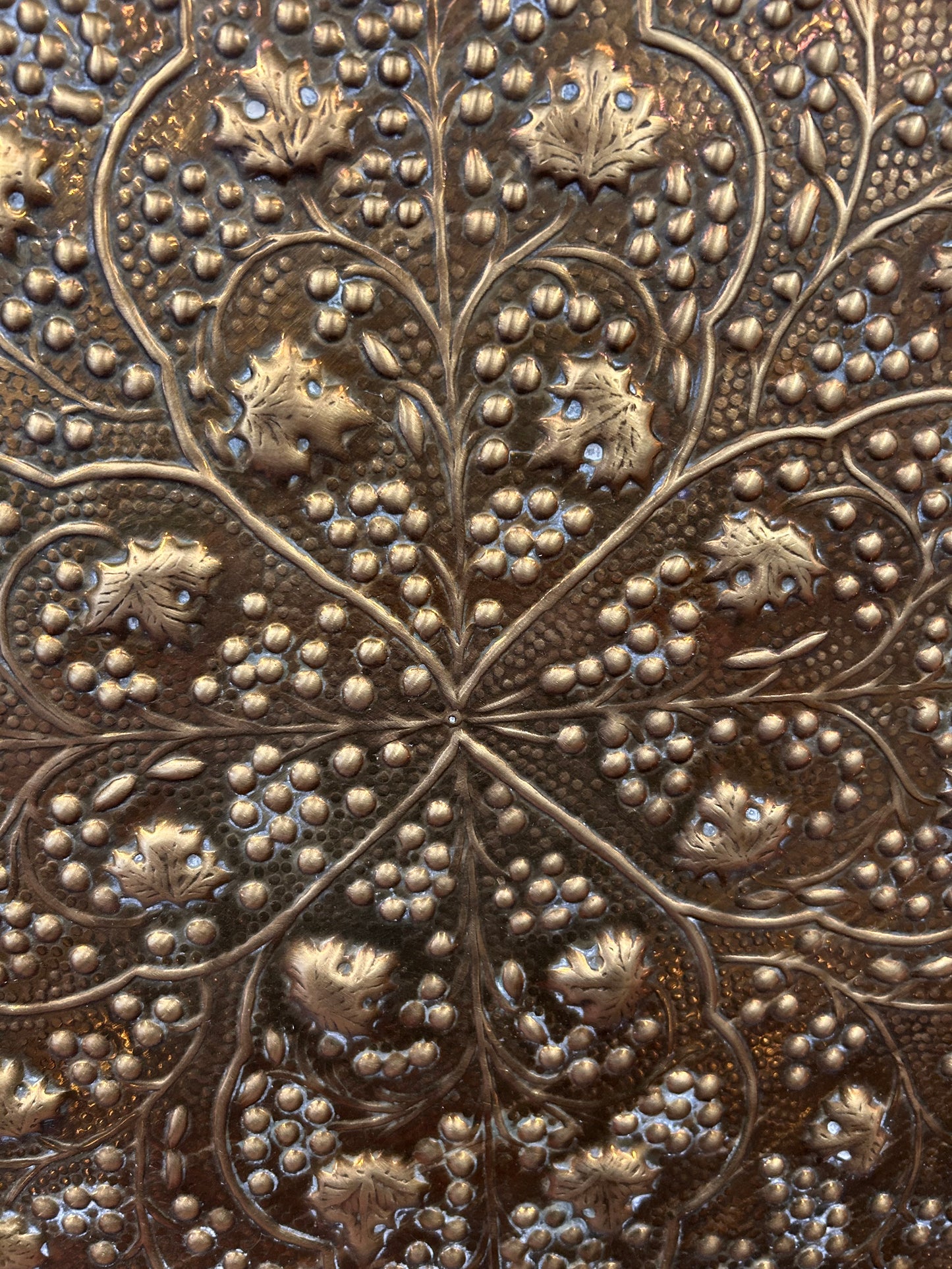 A large brass eastern charger with embossed foliate design