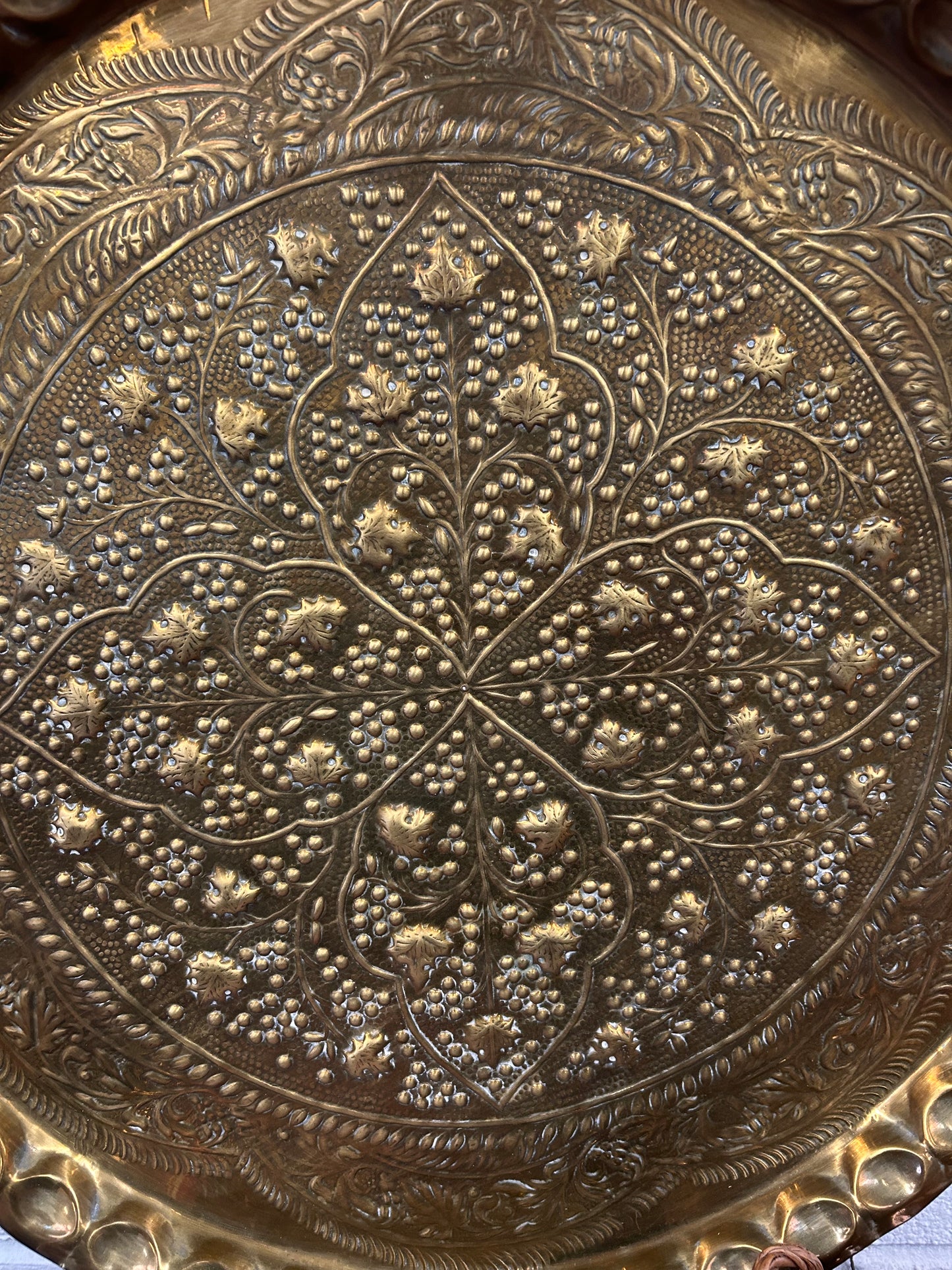 A large brass eastern charger with embossed foliate design