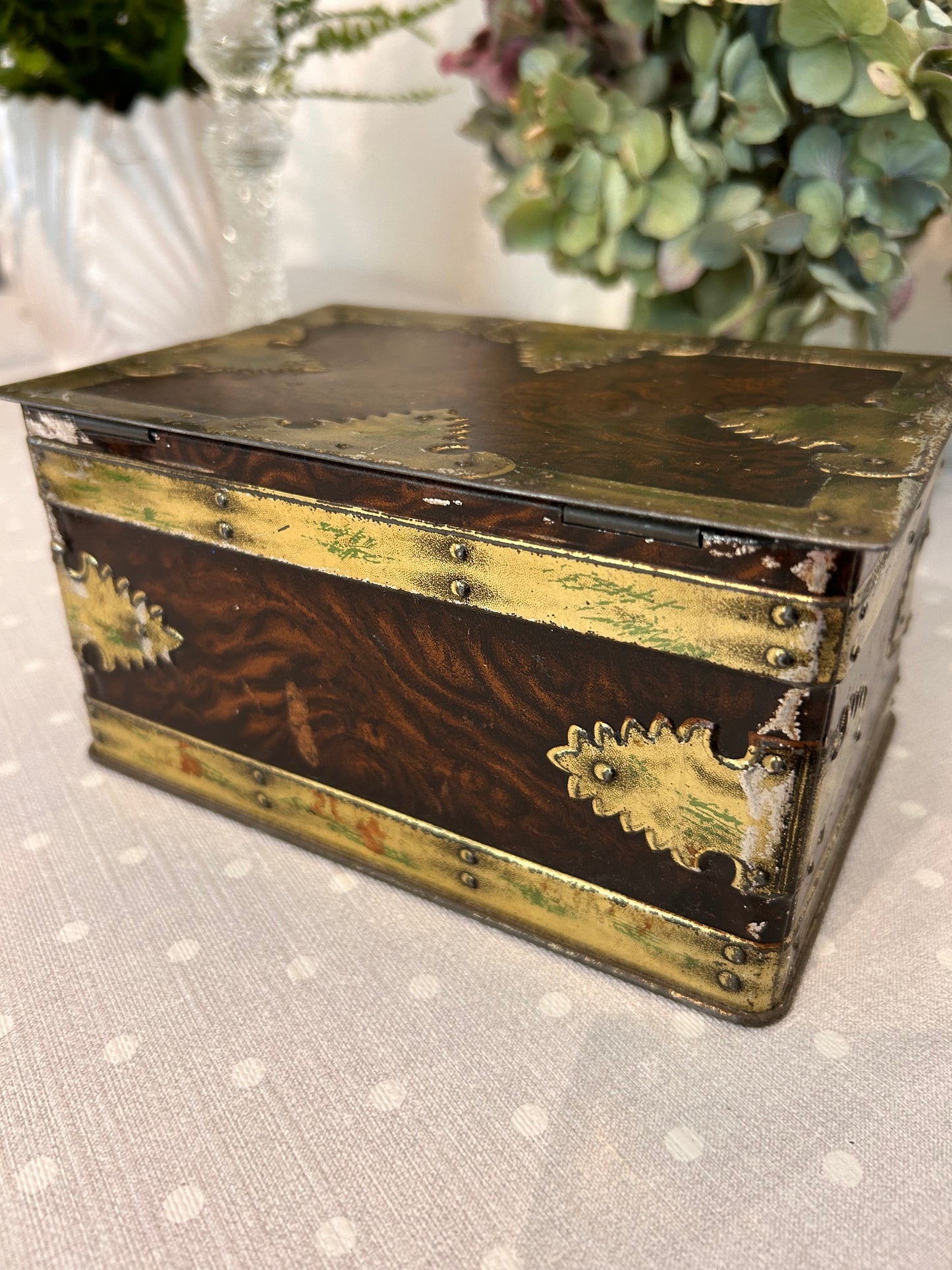 A vintage metal tin storage box resembling brass mounted wood.