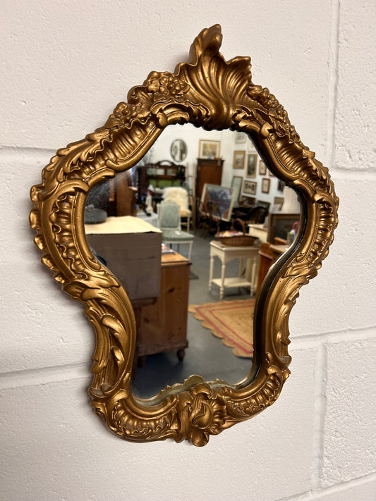 Small shield shape ornate mid-century decorative framed mirror.