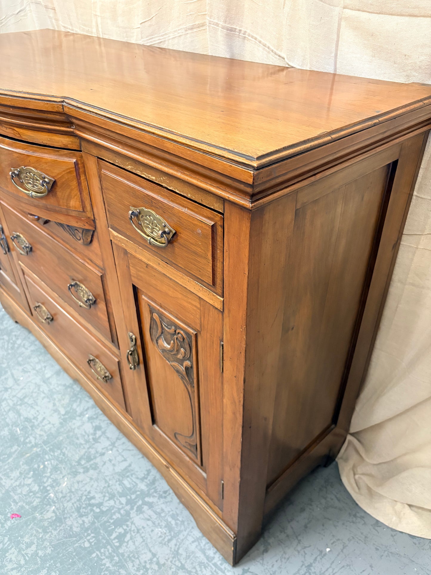 Edwardian Walnut sideboard featuring carved floral panels doors and brass hardware