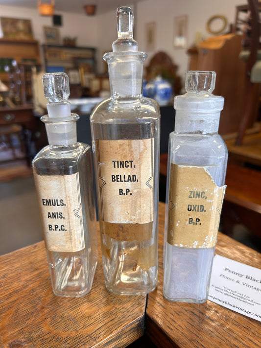 Three Victorian apothecary chemists bottles with labels and ground glass stoppers.