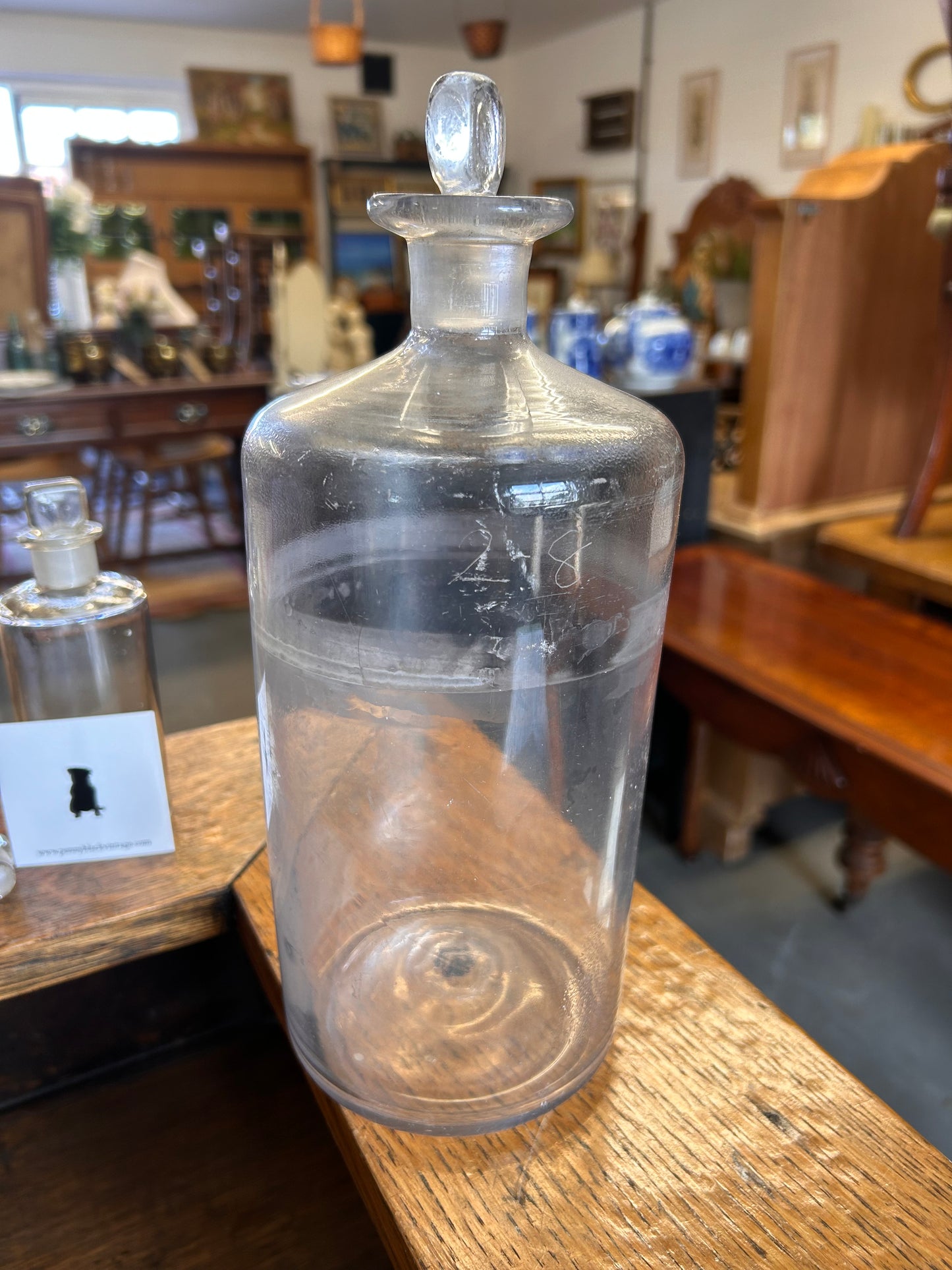 One large plain glass apothecary bottle with ground glass stopper.