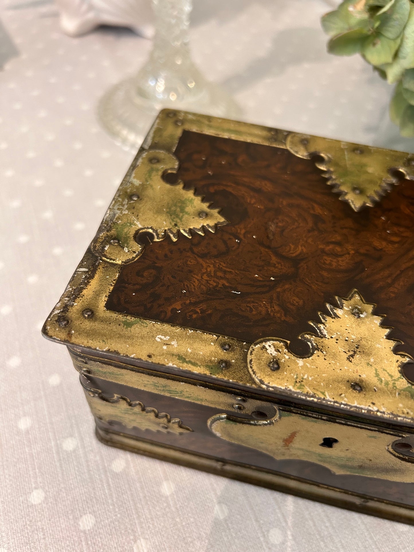 A vintage metal tin storage box resembling brass mounted wood.