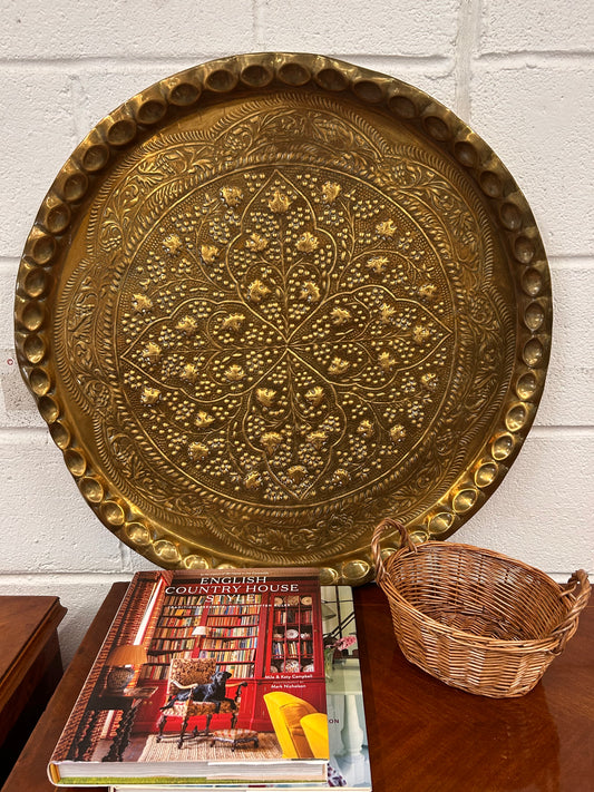 A large brass eastern charger with embossed foliate design