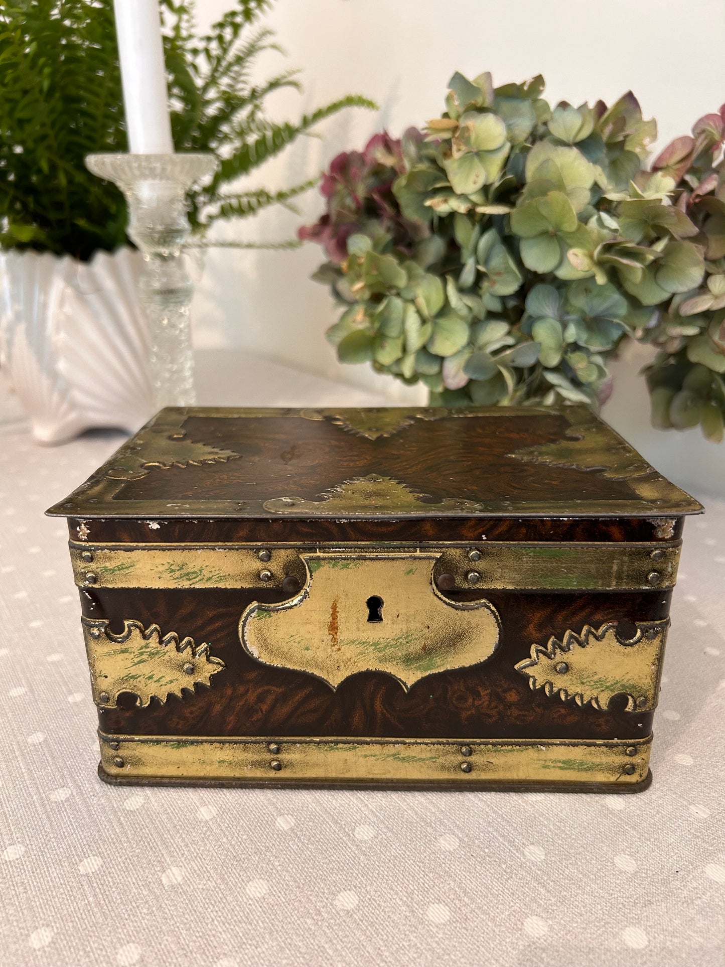 A vintage metal tin storage box resembling brass mounted wood.