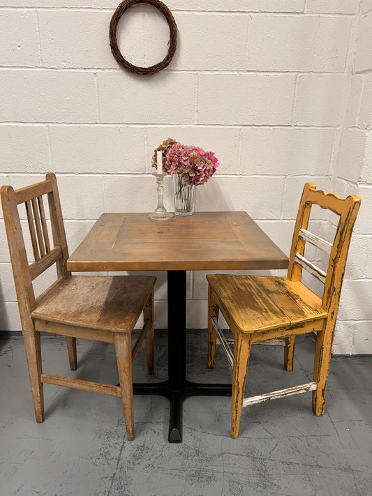 Rustic Preloved two seater table with thick wooden top and black metal base.