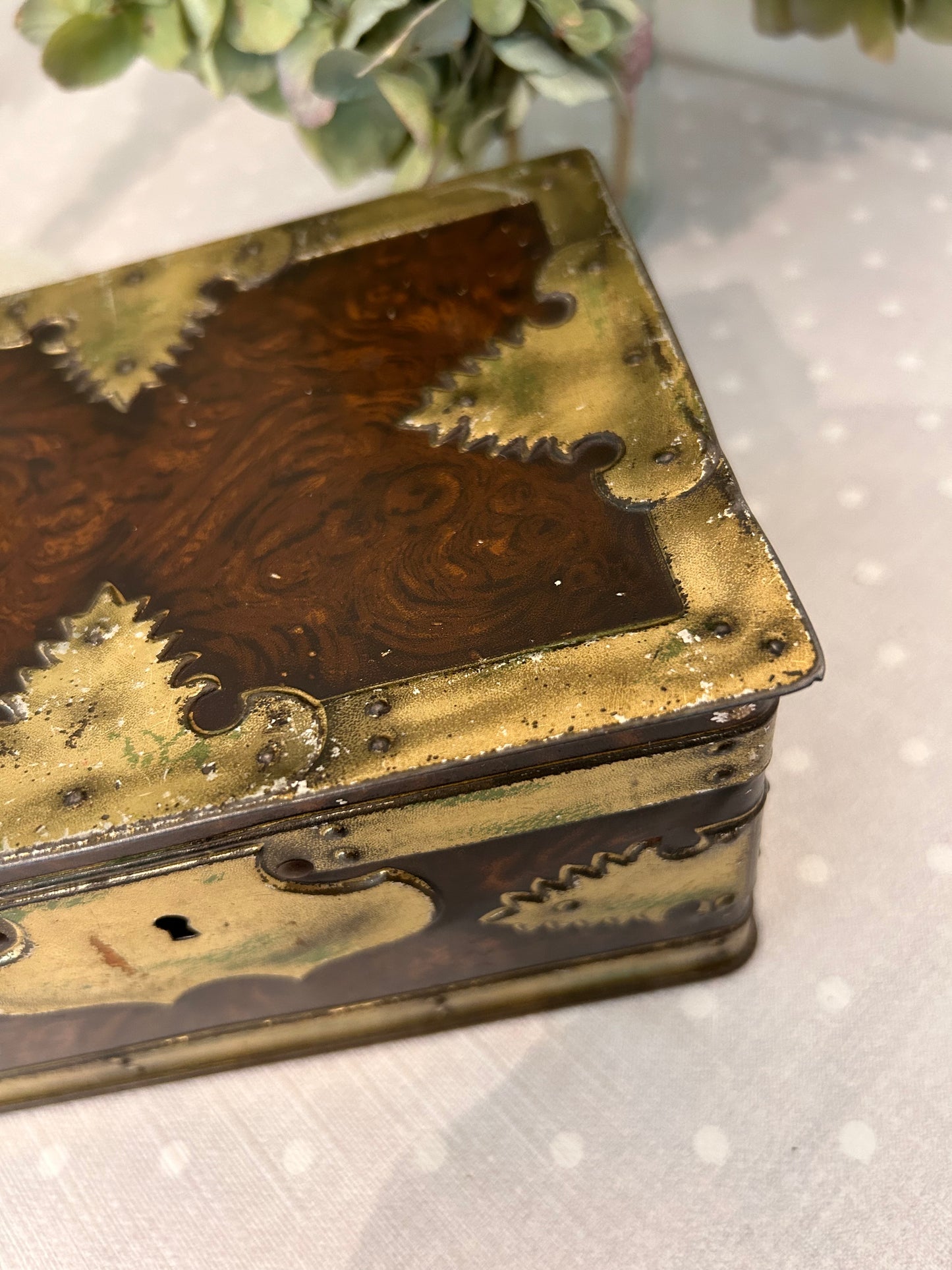 A vintage metal tin storage box resembling brass mounted wood.